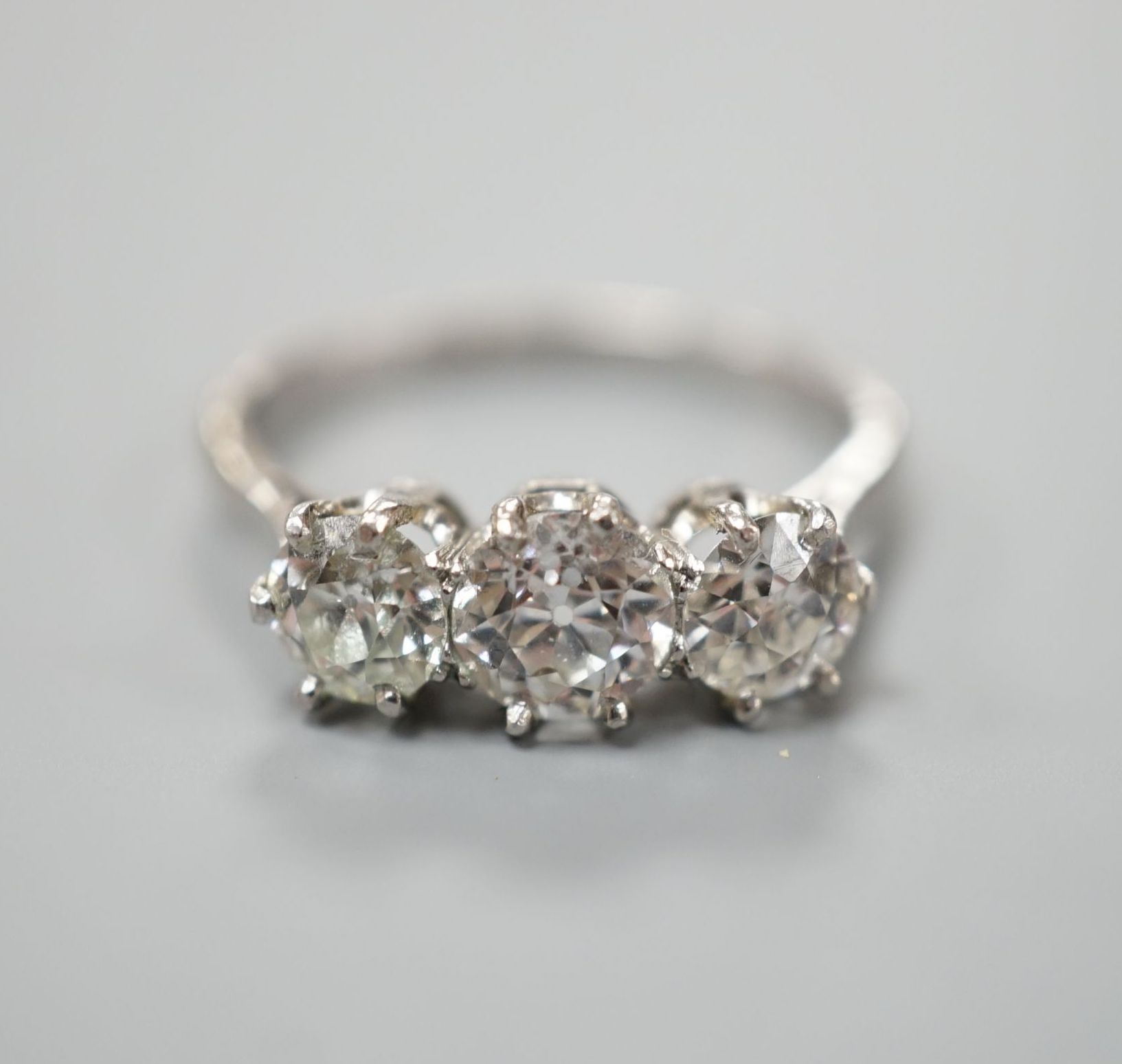 A white metal (stamped Plat) and three stone diamond set ring, size P/Q, gross weight 3.7 grams